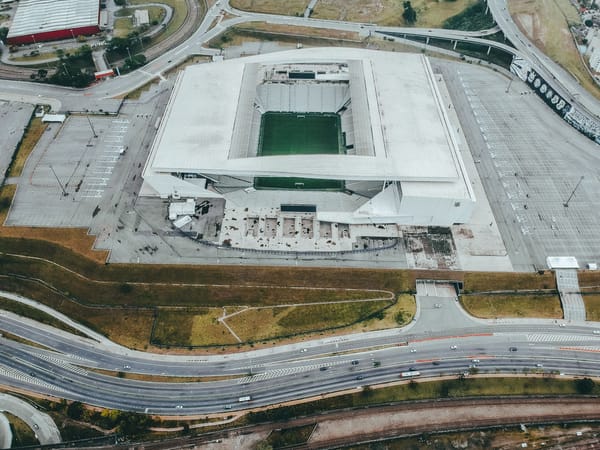 High-angle shot of a modern stadium with an empty parking lot and surrounding roads.